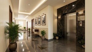 A hotel lobby with a polished floor, wall-mounted artwork, a reception desk, and an elevator with a lift-only sign.