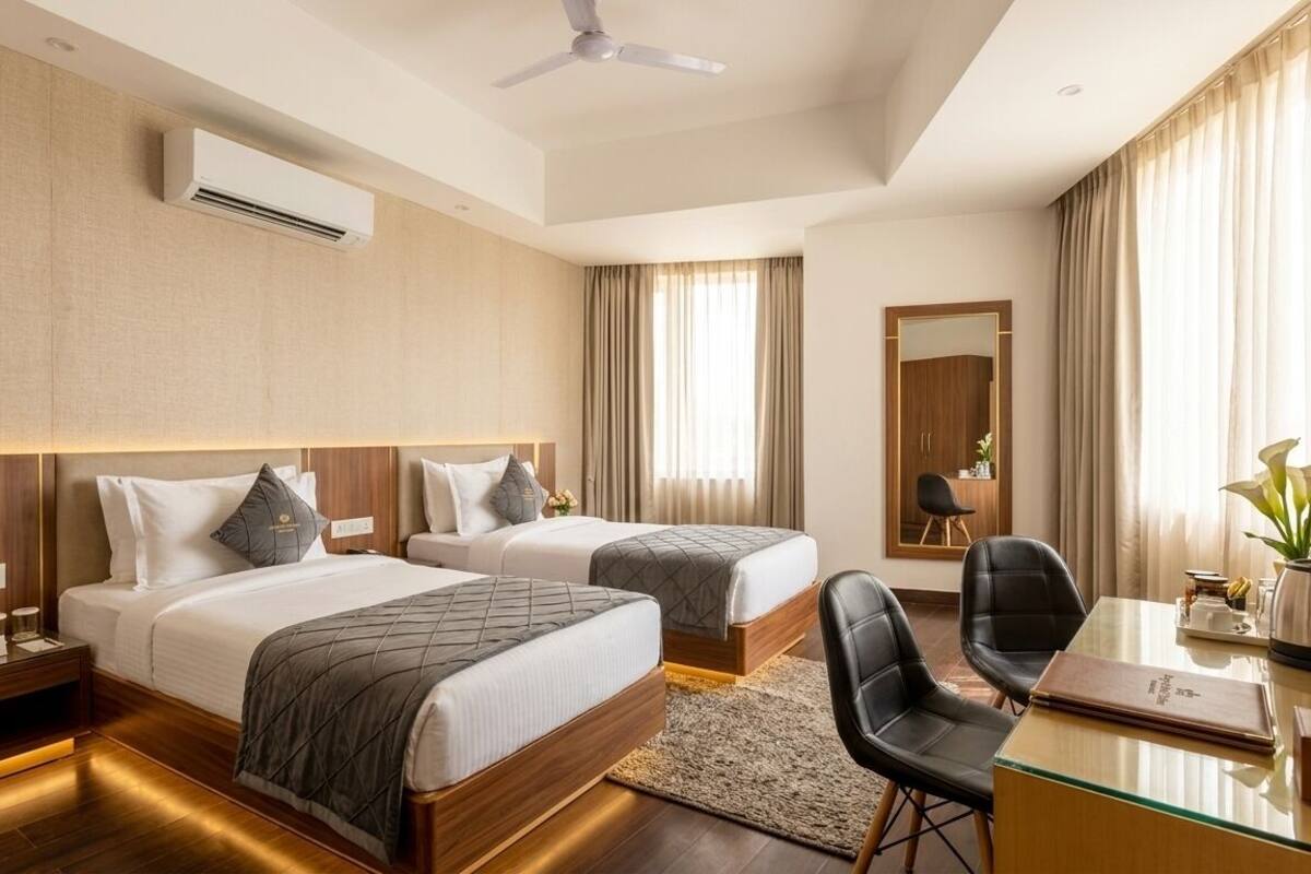 Une chambre d’hôtel avec deux lits, un bureau, une chaise, un climatiseur et un ventilateur de plafond.