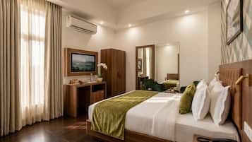 A hotel room with a bed, a desk, a television, a mirror, and a window with curtains.