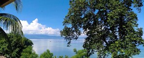 A view of a calm lake with boats, surrounded by lush greenery and trees. - Panorama Backpackers (Pulau Bunaken)