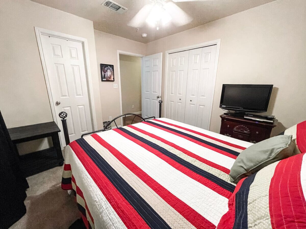 A bedroom with a bed, a TV, and a dresser.