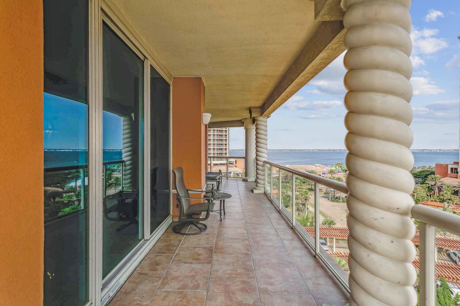 Un balcone con vista sul mare, un corrimano e qualche sedia.