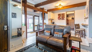 Un salon chaleureux avec un canapé en cuir, des poutres en bois et un tapis à motifs.