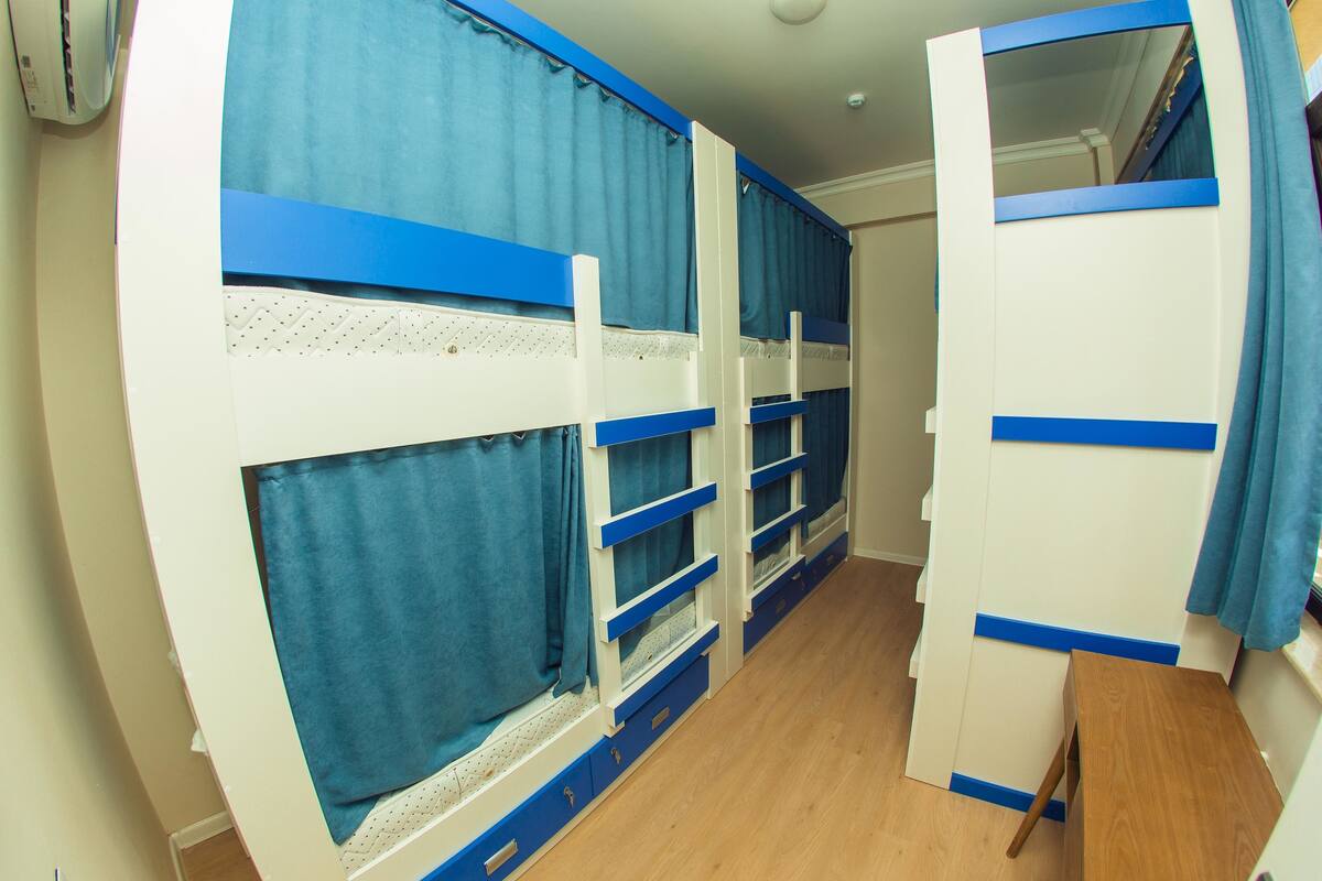 Une chambre avec des lits superposés, un bureau en bois et une fenêtre avec des rideaux.