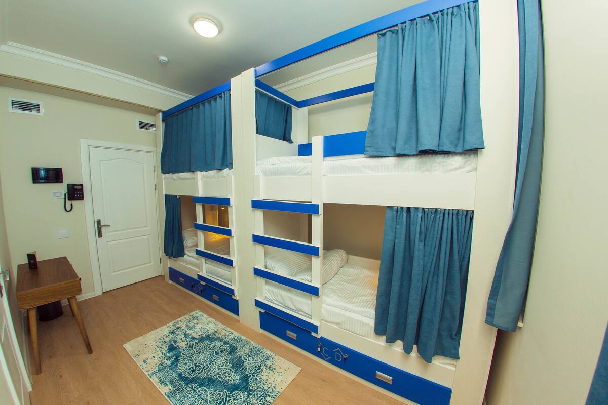 Une chambre avec des lits superposés, un bureau et un tapis à motifs.