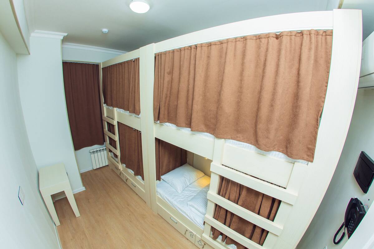 Une chambre avec un lit superposé, une petite table et un radiateur.