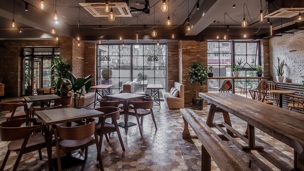 Una cafeteria moderna amb un paviment de disseny hexagonal, mobles de fusta i grans finestres que ofereixen vistes a la ciutat.