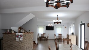 Ein geräumiger Essbereich mit einem langen Tisch, Holzstühlen und einer Kristallleuchter.