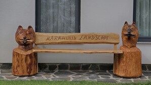 Eine hölzerne Bank mit Reliefs von Tierköpfen und dem Text "MURAUMES LANDSCAPE".