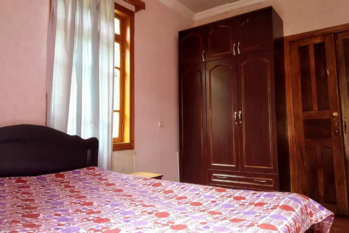 Un dormitorio con cama, armario y ventana con cortinas.