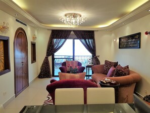 A living room with a chandelier, a sofa, a chair, and a dining table. - Green Hill Village (Bchamoun)