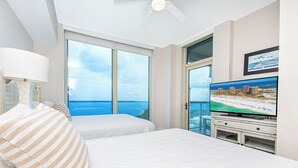 Ein Hotelzimmer mit zwei Betten, einem Fernseher und Blick aufs Meer.