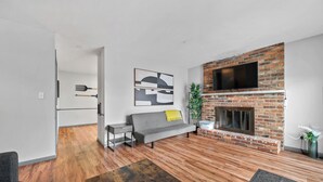 Ein modernes Wohnzimmer mit Kamin, einer Couch, einem Couchtisch und einem an der Wand montierten Fernseher.