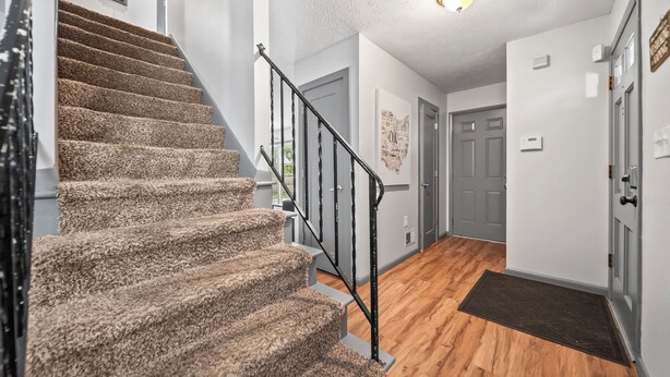 Ein Teppichbelag, eine Metallgeländer und Holzdielen an einer Treppe, sowie eine Tür am Fuß.