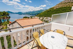 Balcón con mesa y sillas que da a una ciudad costera y montañas.