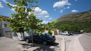 Ein Parkplatz mit Autos, einem Baum und einem Gebäude mit einer Treppe.