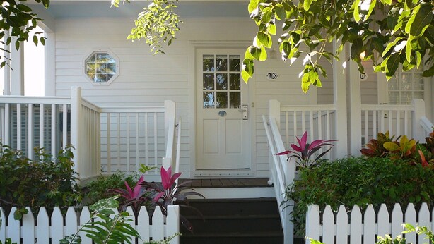 A white house with a front door, a small porch, and a white picket fence. - PLUNGE POOL VILLA ON BLUE WATER LAGOON DUCK Key/MARATHON, FL (Marathon)