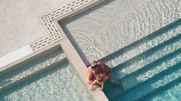 A swimming pool with clear water, tiled edges, and a tiled deck area.