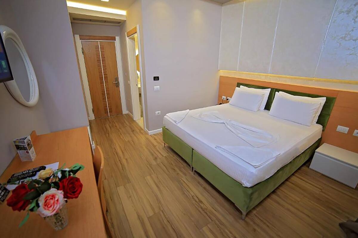 Een hotelkamer met een bed, nachtkastje en een aan de muur bevestigde televisie.