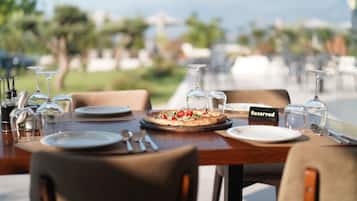 Une table dressée dans un restaurant avec une terrasse, avec des assiettes, des couverts et une pizza, et un panneau indiquant « Réservé ».