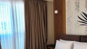 Habitación de hotel con una cama grande, vistas de la ciudad a través de la ventana y una pared con textura.