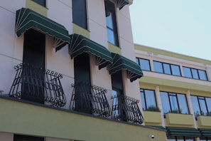 Un edificio con balcones, toldos verdes y barandillas de hierro forjado.