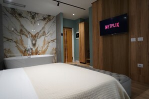 Una habitación de hotel moderna con una cama grande, una pared de mármol, un panel de pared de madera y un televisor mostrando 'NETFLIX'.