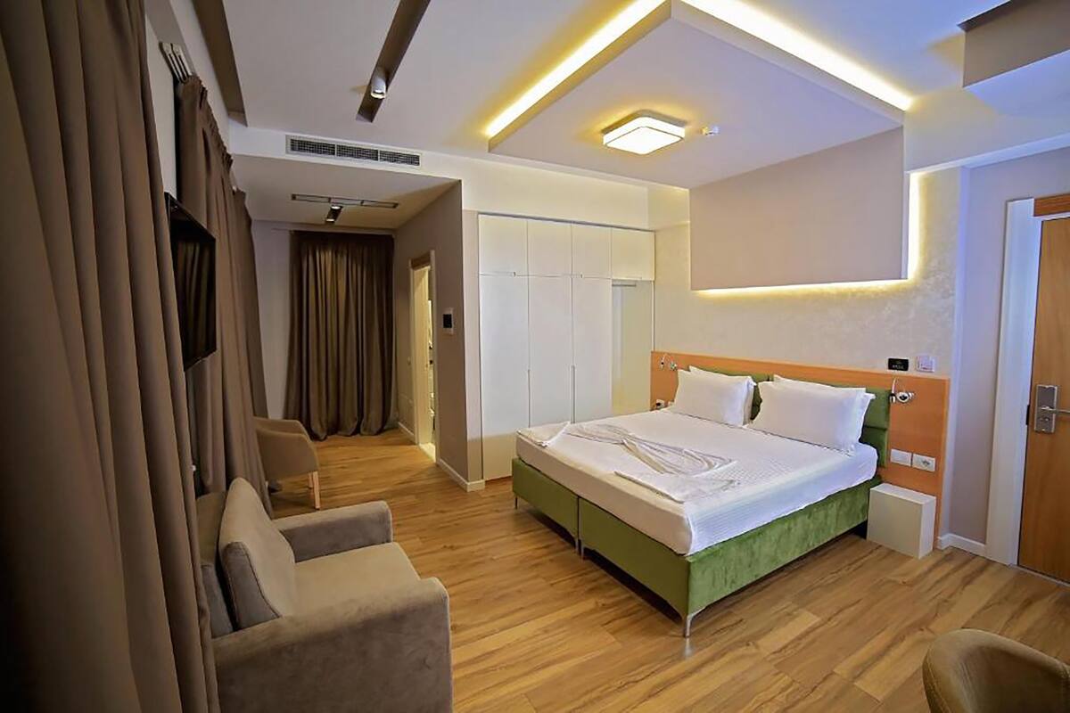 Een moderne hotelkamer met een groot bed, een zithoek met stoelen en een inloopkast.