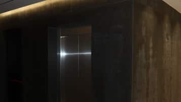 Un ascensor moderno con acabados metálicos, al lado de una pared con textura.
