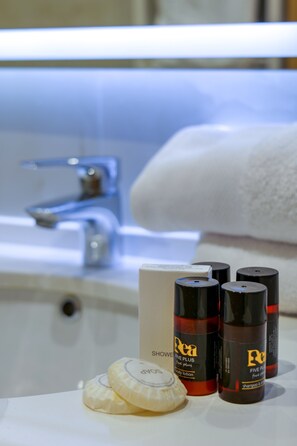 A bathroom with a sink, a towel, and three bottles of shampoo and conditioner. - Lord Hotel & Restaurant at AutoStation (Preze)