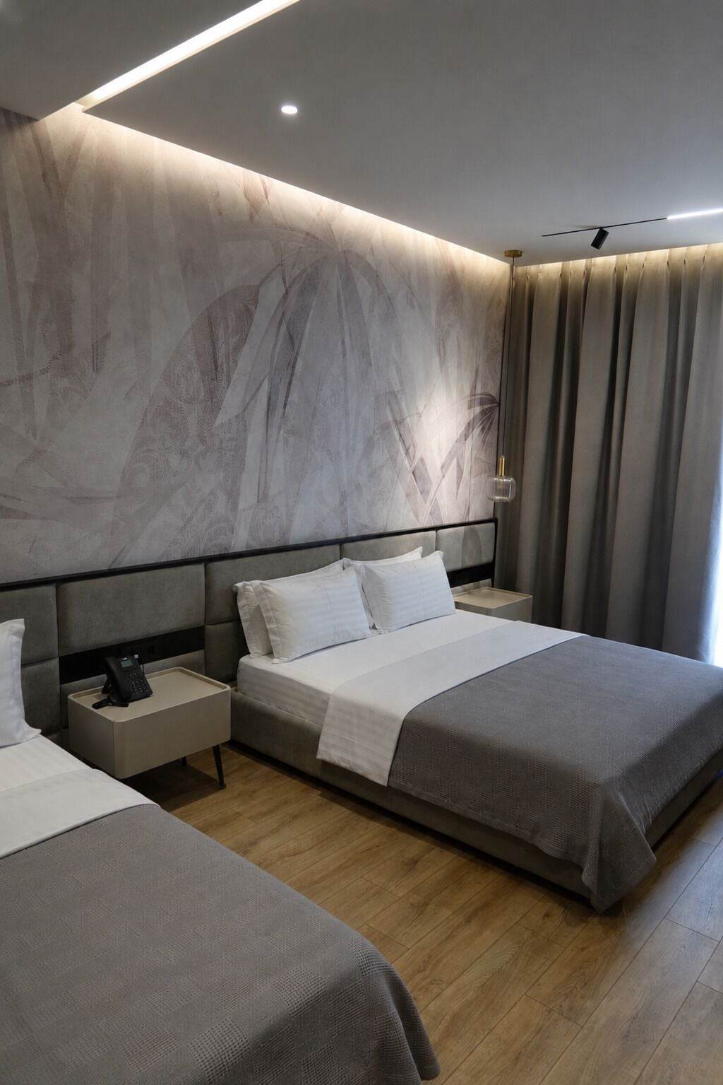 Ein modernes Hotelzimmer mit einem großen Bett, Nachttischen und einer Wand mit Marmoroptik.
