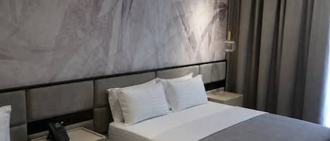 A modern hotel room with a large bed, bedside tables, and a wall with a marble-like design.