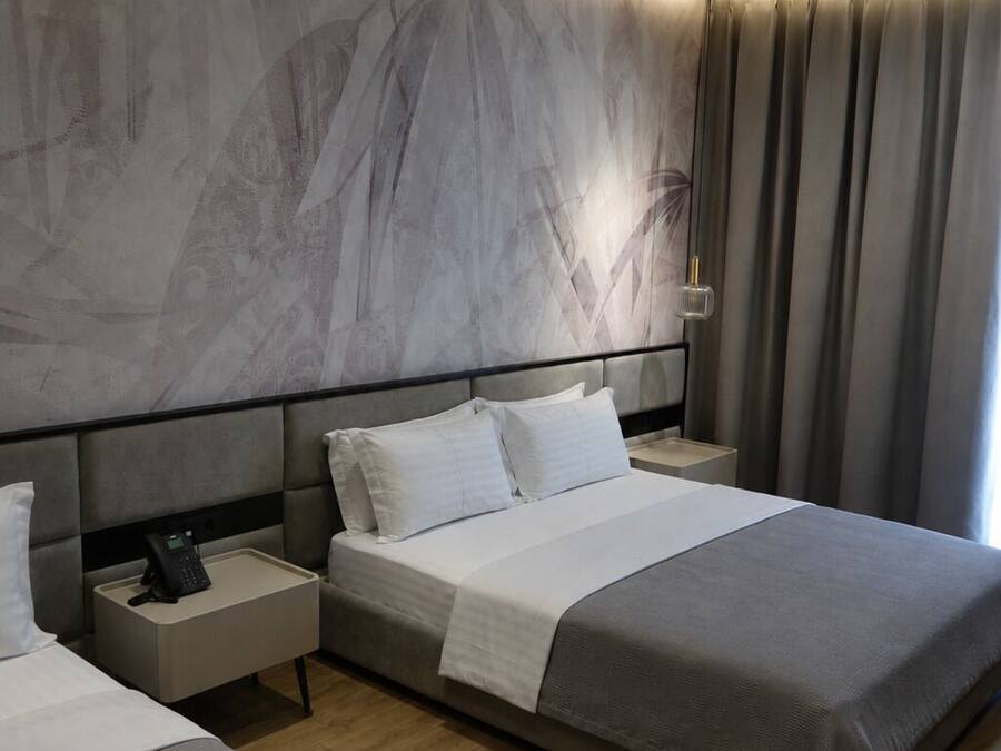Ein modernes Hotelzimmer mit einem großen Bett, Nachttischen und einer Wand mit Marmoroptik.