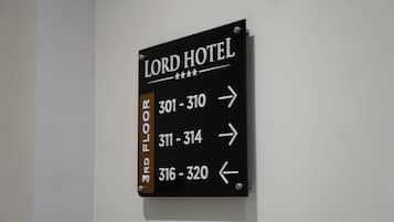 Señal negra con letras blancas que indica los números de habitación y las indicaciones para el primer piso del Hotel Lord.