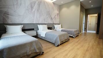 Habitación de hotel con tres camas, un amplio mural abstracto en la pared y suelo de madera.