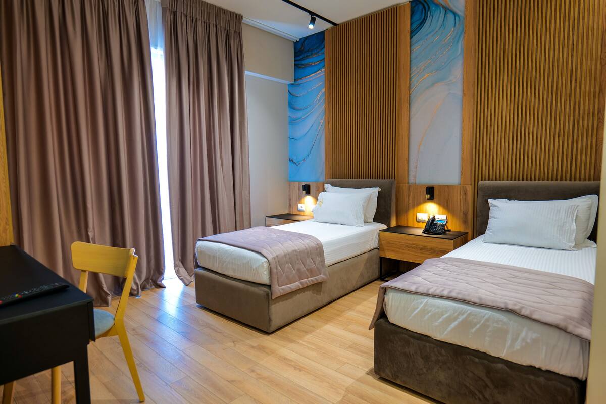 Een hotelkamer met twee bedden, een bureau en een stoel.