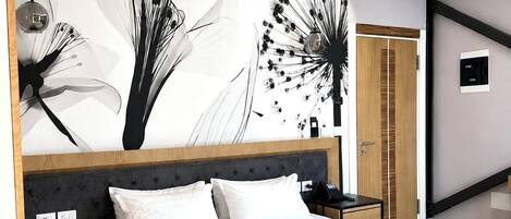 Un dormitorio moderno con una cama grande, una mesita de noche, un aparador y un aplique de pared.