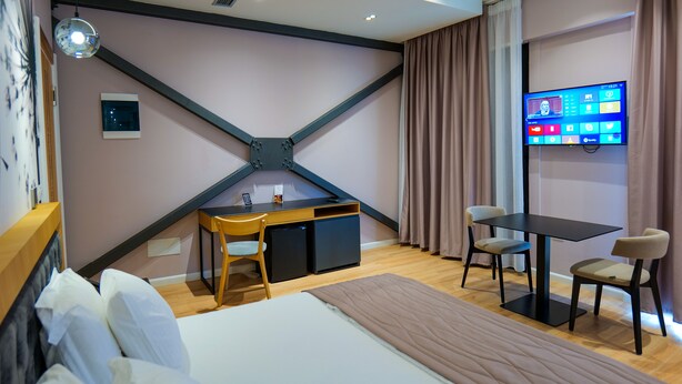Una habitación de hotel moderna con cama, escritorio y televisión.
