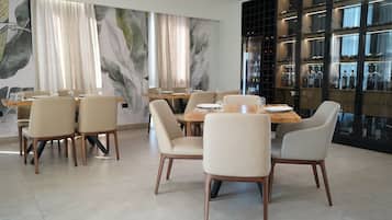 Uma área de refeições moderna com uma mesa redonda, seis cadeiras e um grande mural na parede.