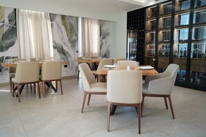 A modern dining area with a round table, six chairs, and a large wall mural. - Lord Hotel & Restaurant at AutoStation (Preze)