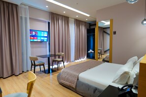 A hotel room with a bed, a desk with a chair, a TV mounted on the wall, and a wardrobe. - Lord Hotel & Restaurant at AutoStation (Preze)