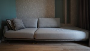 Una sala de estar moderna y minimalista, con un sofá gris, una mesita y una pared lisa.