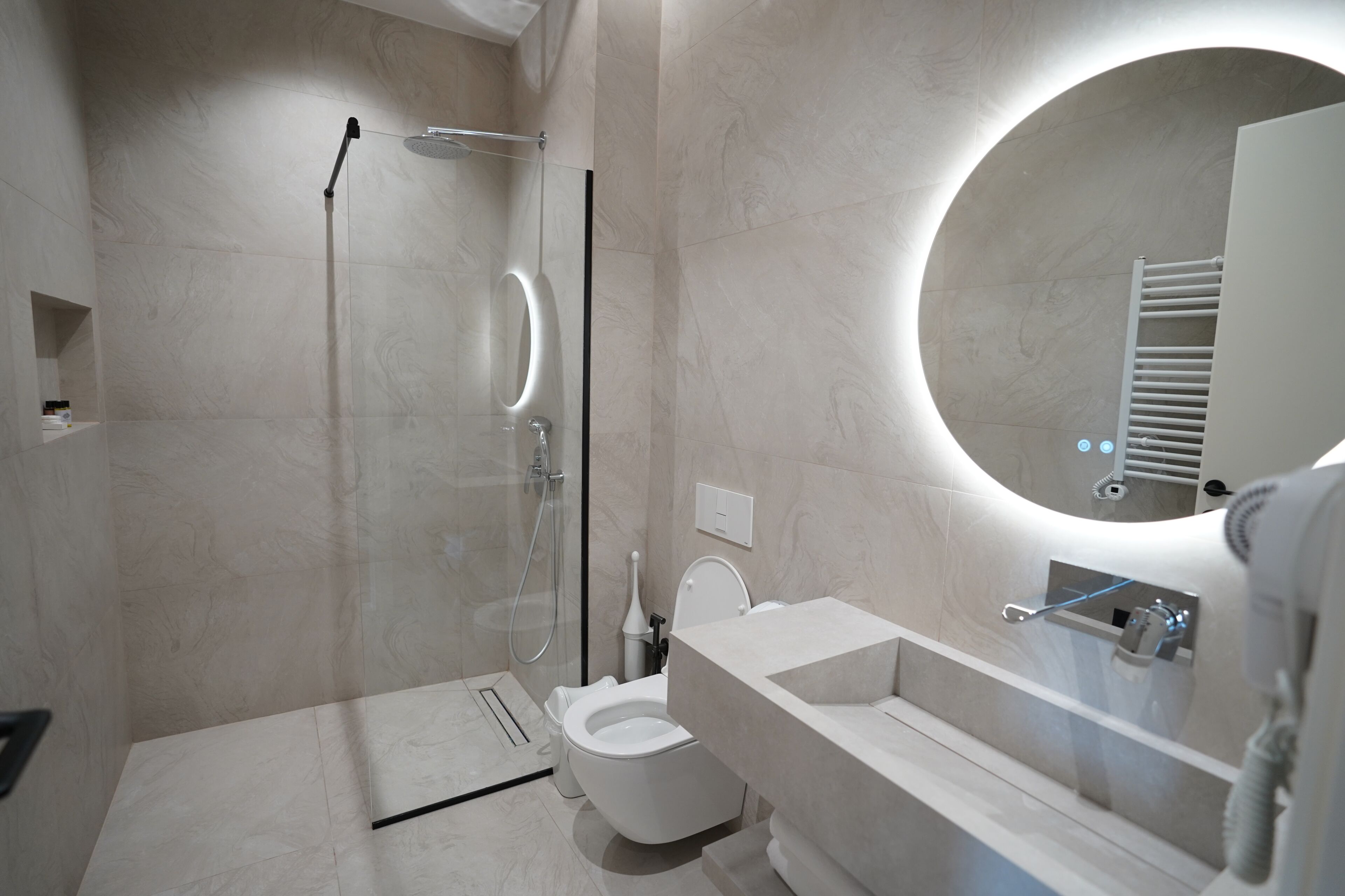 Un baño moderno con cabina de ducha de vidrio, inodoro y lavamanos con espejo.
