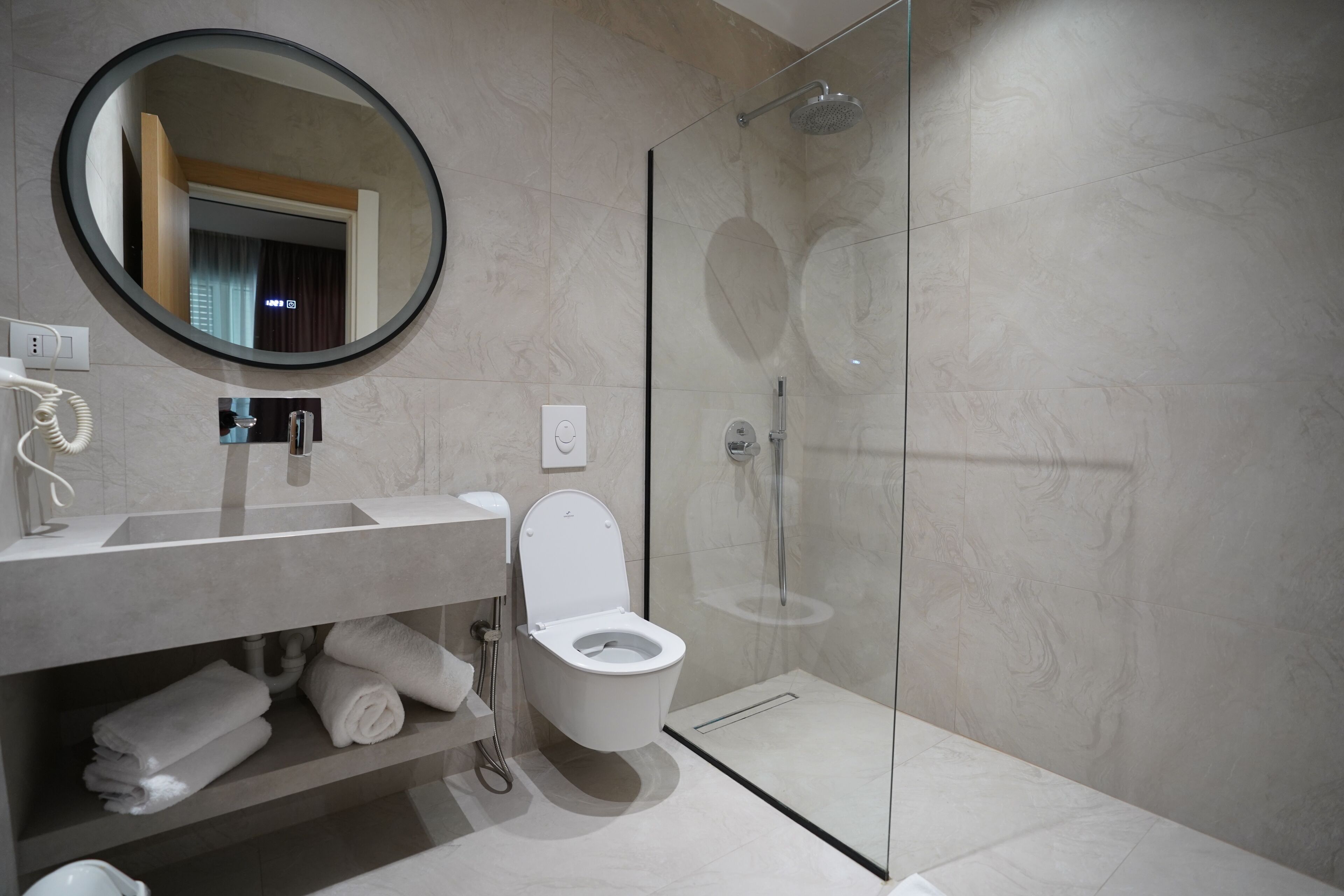 A modern bathroom with a glass-enclosed shower, a toilet, and a sink with a mirror above it.