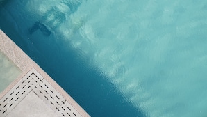 Una piscina con superficie de agua cristalina y una escalera.