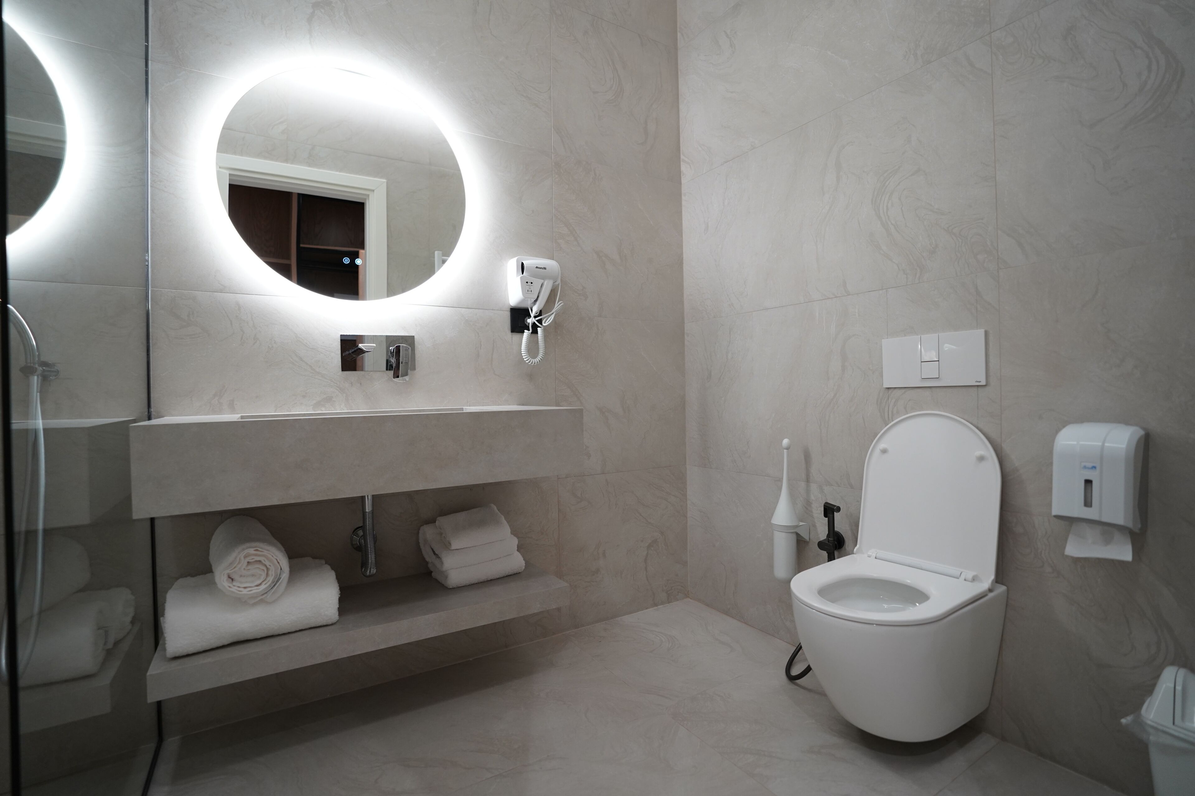 A modern bathroom with a toilet, sink, and mirror.