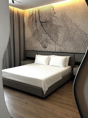 A modern bedroom with a large bed, a headboard with a tree design, and a wooden floor.