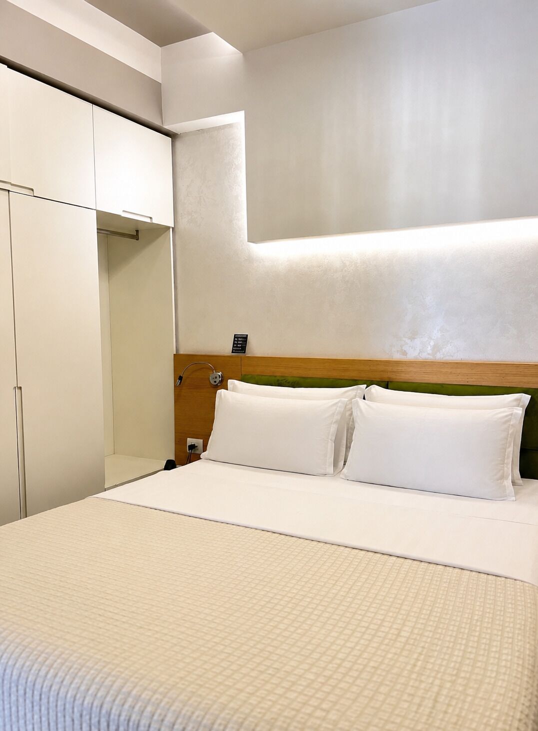 Ein Hotelzimmer mit einem Bett, einem Kleiderschrank und einer Wandleuchte.