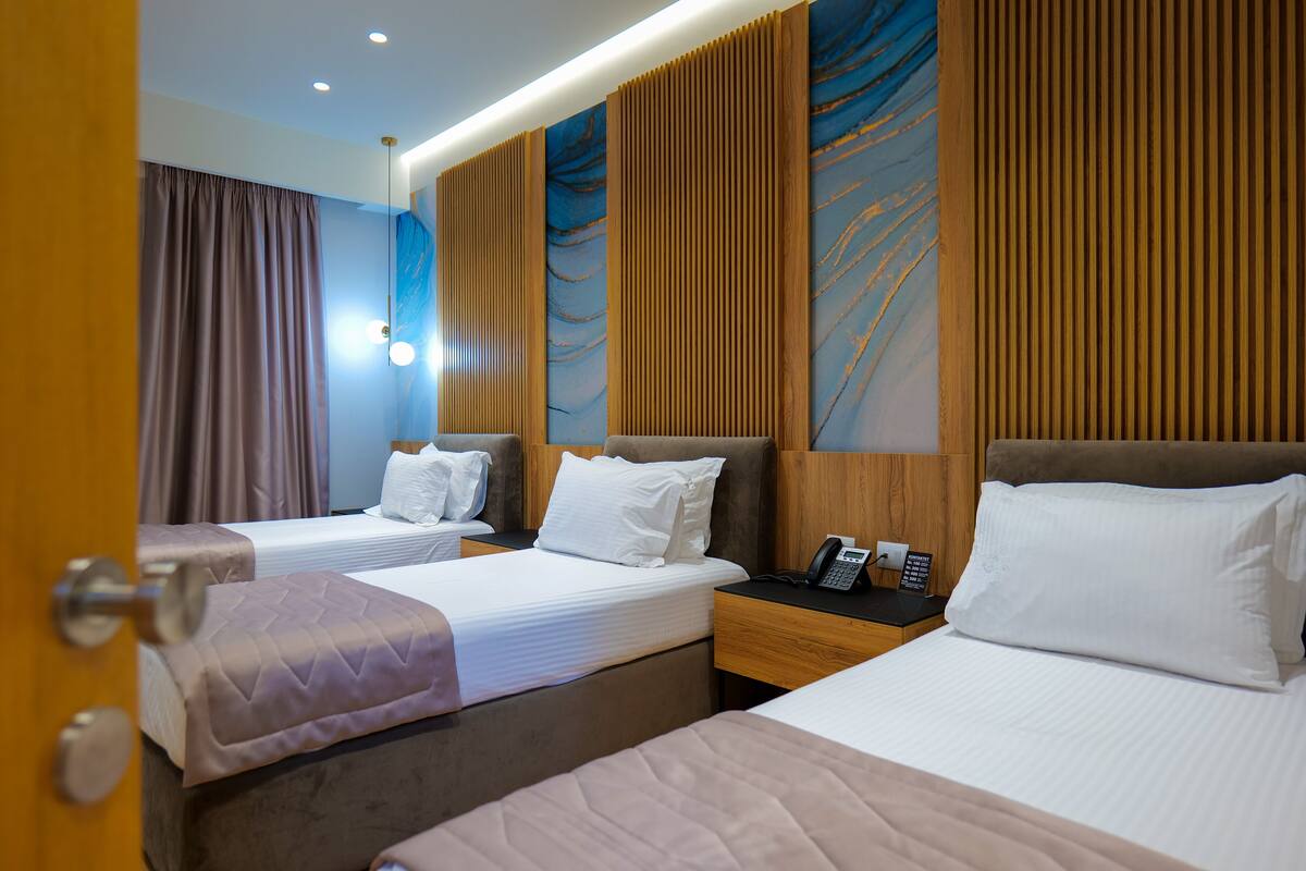 Een hotelkamer met twee bedden, een houten hoofdbord, een telefoon en een muur met een abstract blauw ontwerp.