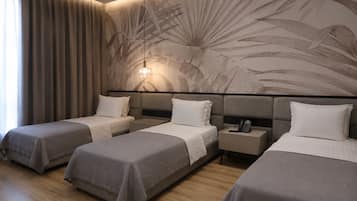 A hotel room with three beds, a large wall mural, and a bedside telephone.